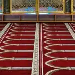 Luxury wall-to-wall red mosque carpet with white pointed arch patterns for grand masjids in Dubai.