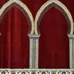 Soft red mosque carpet in Dubai with elegant white and gold arch patterns for masjid prayer hall flooring.