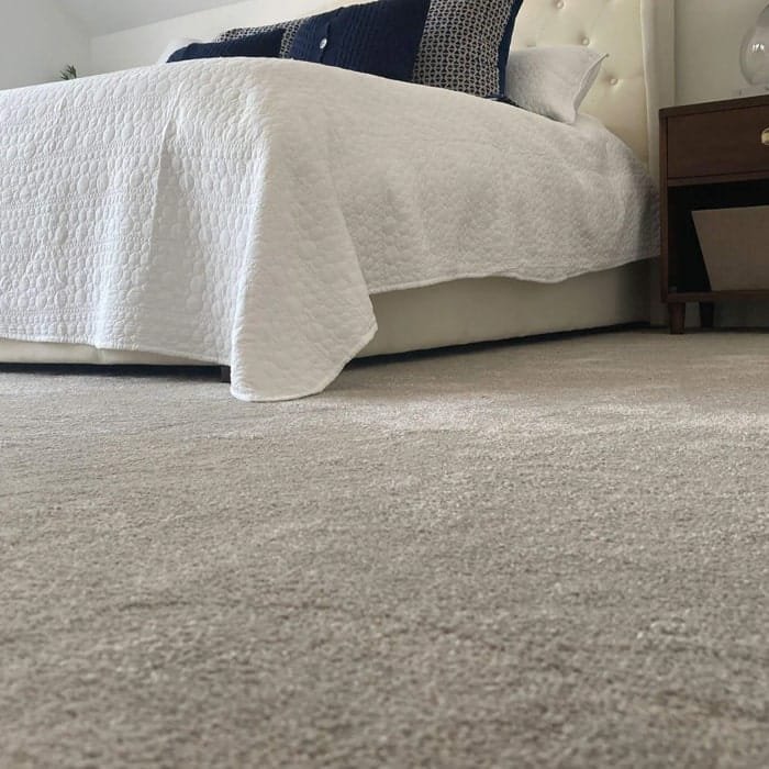 Cream saxony wall to wall carpet under a bed