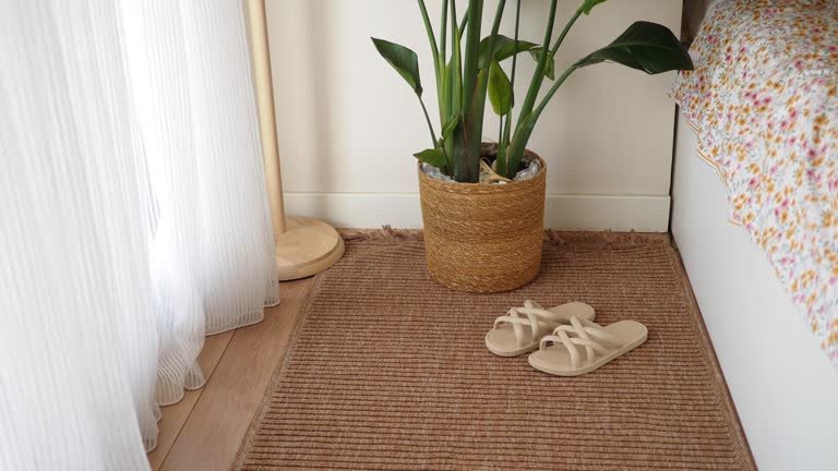 A warm bedroom featuring a relaxed corner with a plant and comfy slippers.