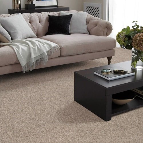 Tan polyester wall to wall carpet under a couch