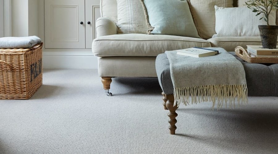Textured grey loop pile carpet under a sofa